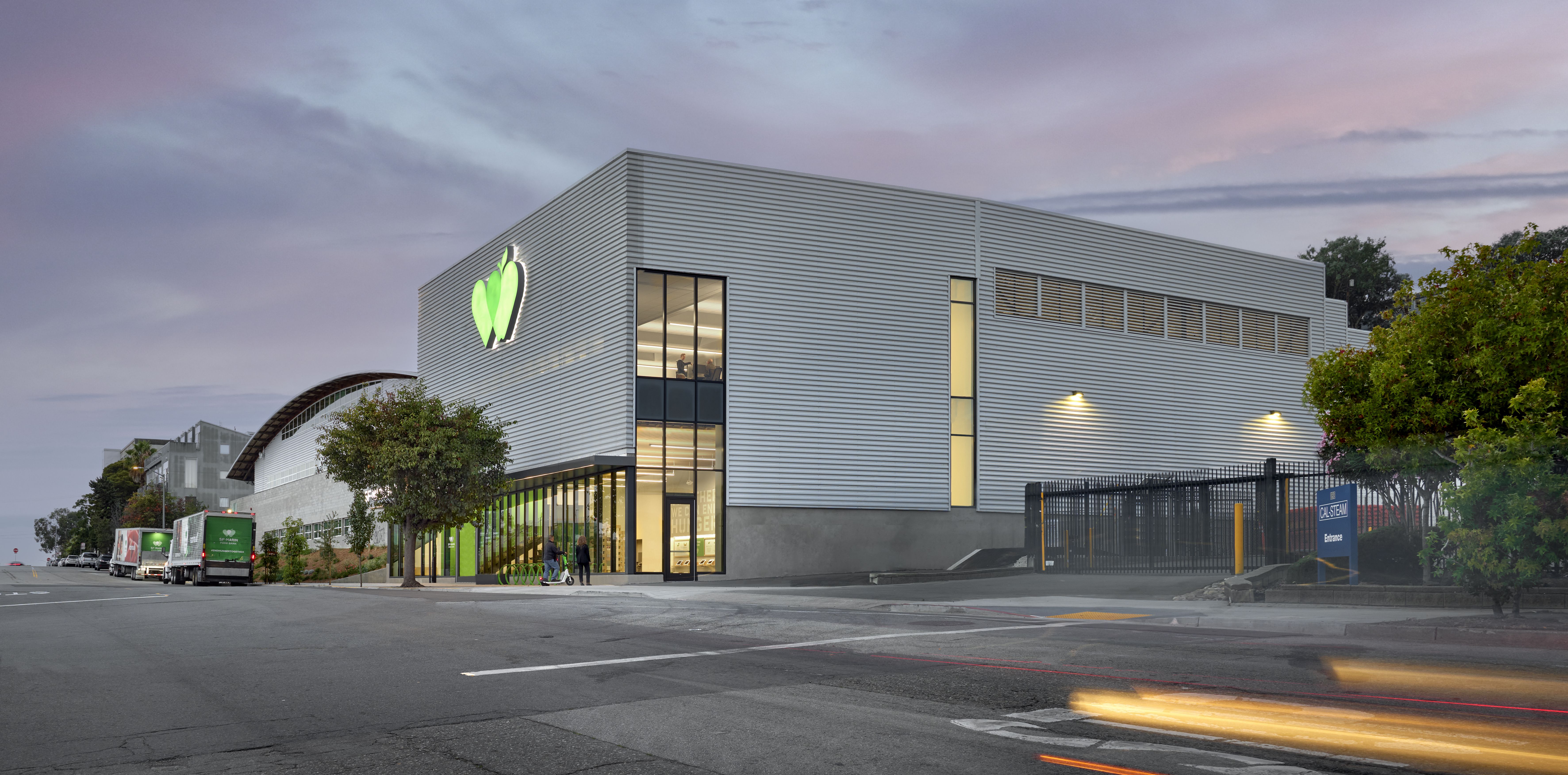 Corner view of building with logo from across the street at dusk.