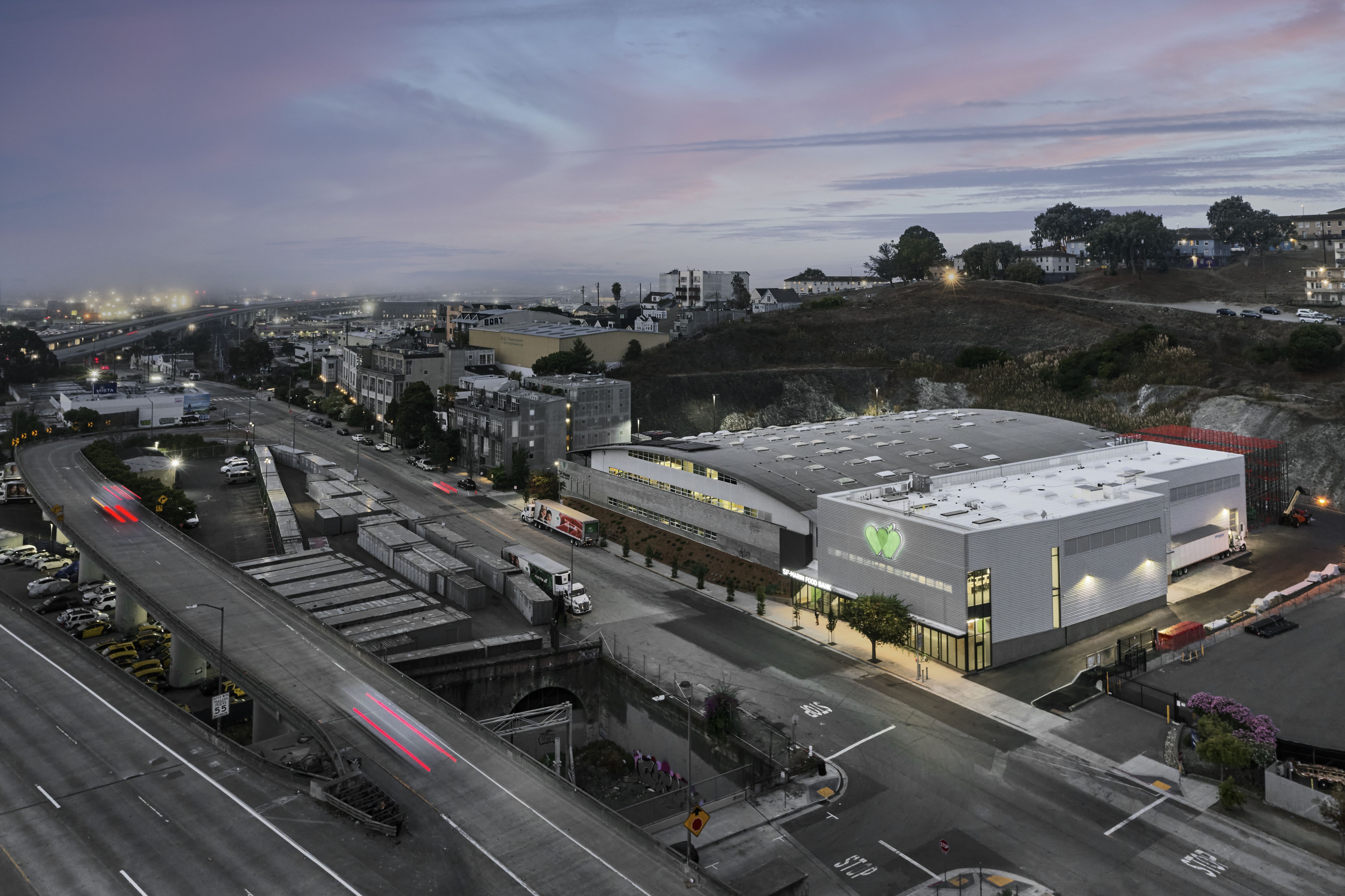 Arial view of building showing streets and freeway in foreground at dusk.