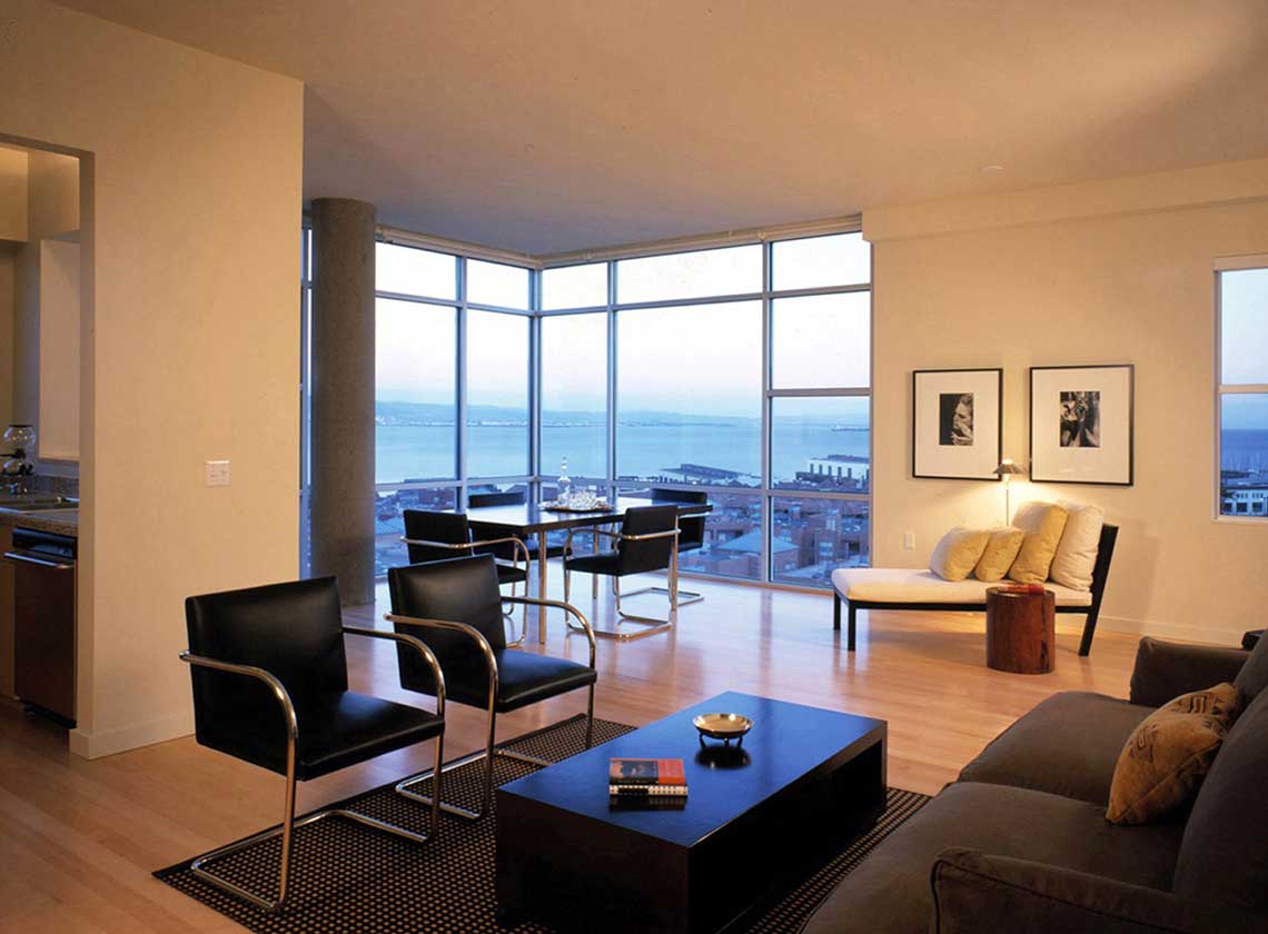 Interior evening view of furnished modern unit interior with views of the bay through floor to ceiling windows