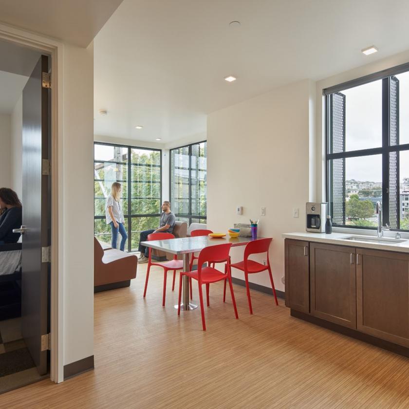 Interior view of shared community kitchenette, dining, and seating area with large windows