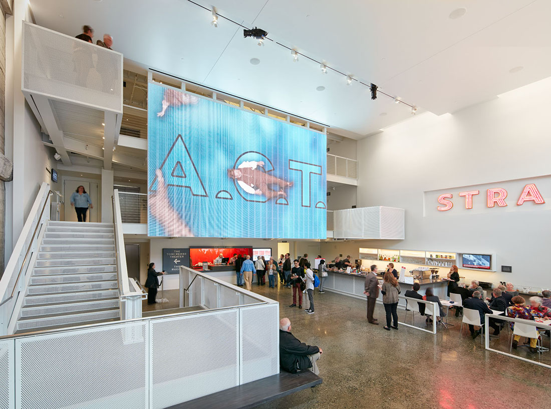 Interior view of lobby with guests mingling and a large digital display spanning two floors.