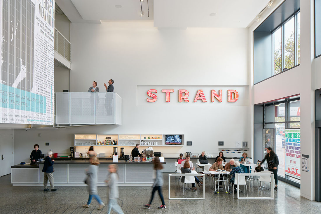 Interior view of lobby concessions with coffee and beverage services and an illuminated sign reading "STRAND" on the wall