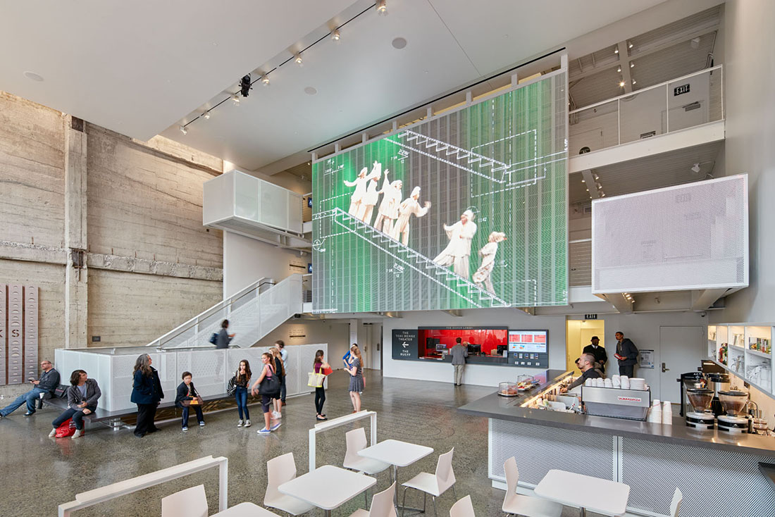 View of interior lobby showing staircases to theater levels and exposed concrete walls