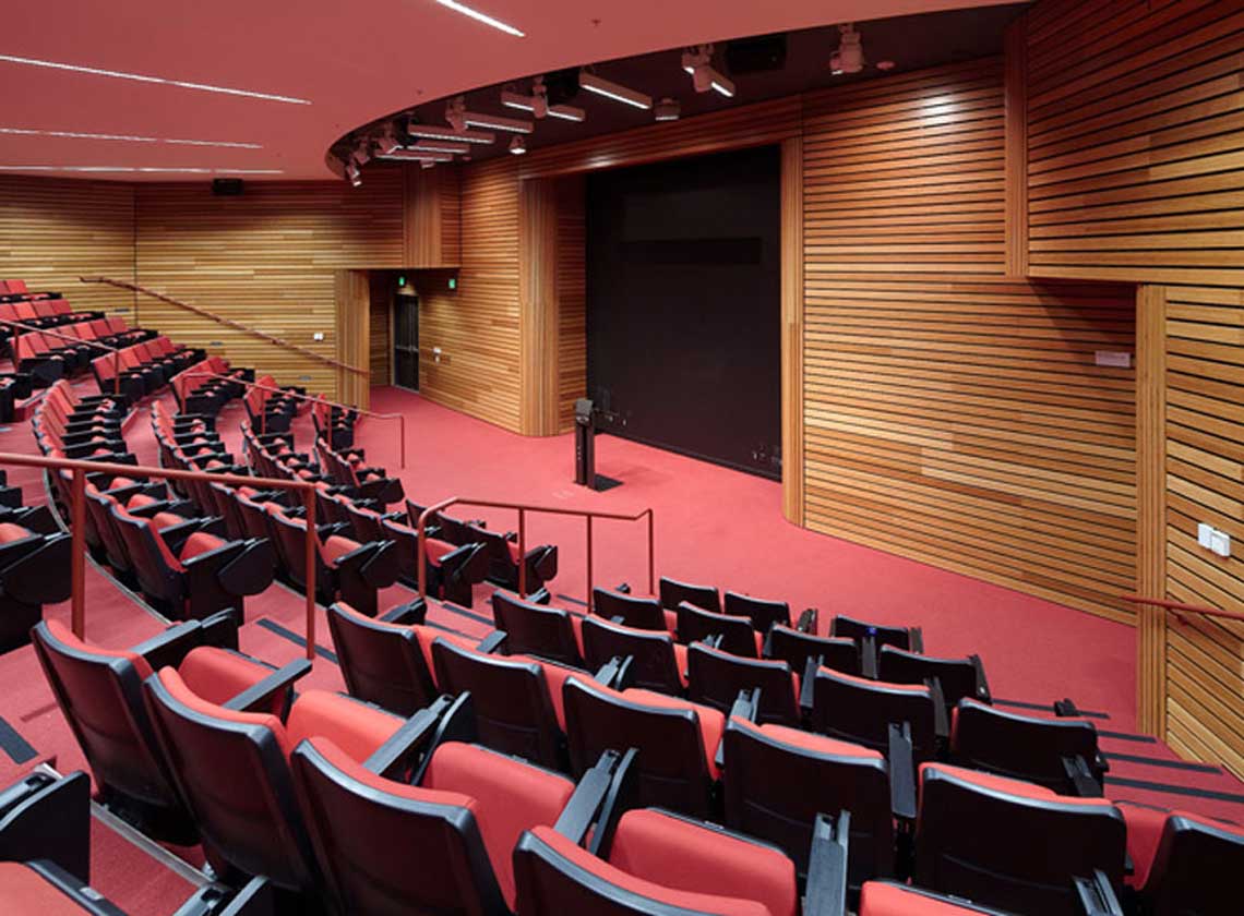 Interior view of theater / meeting space with red seats and carpet with wood panel walls