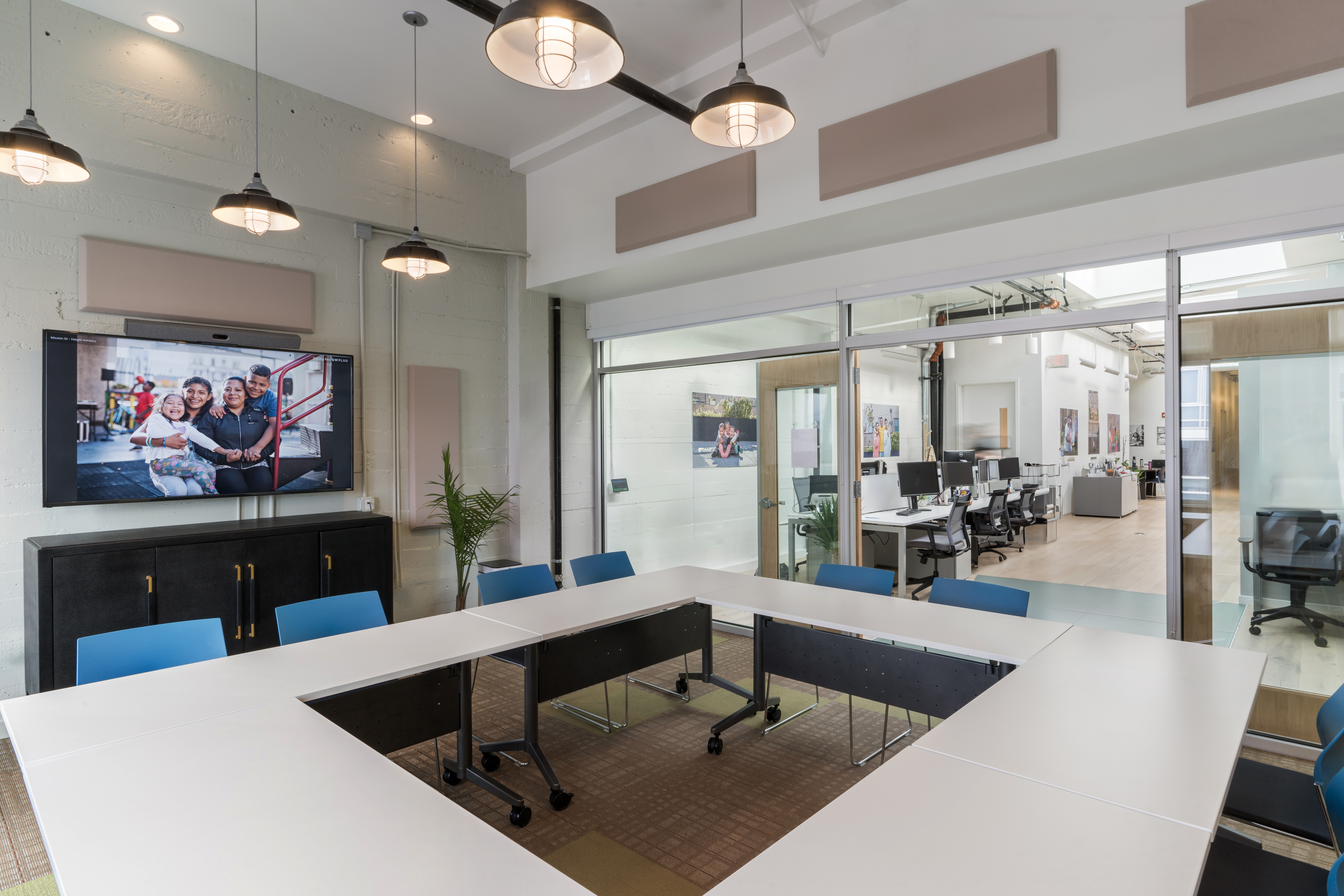 Conference room with seating surrounding square table with video monitor on wall.