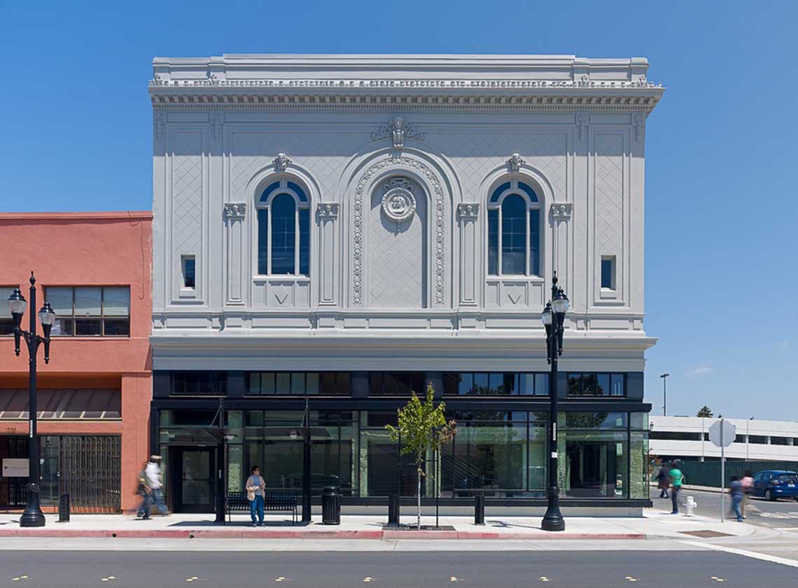 Front view of ornate building façade with renovated ground-floor glass storefront