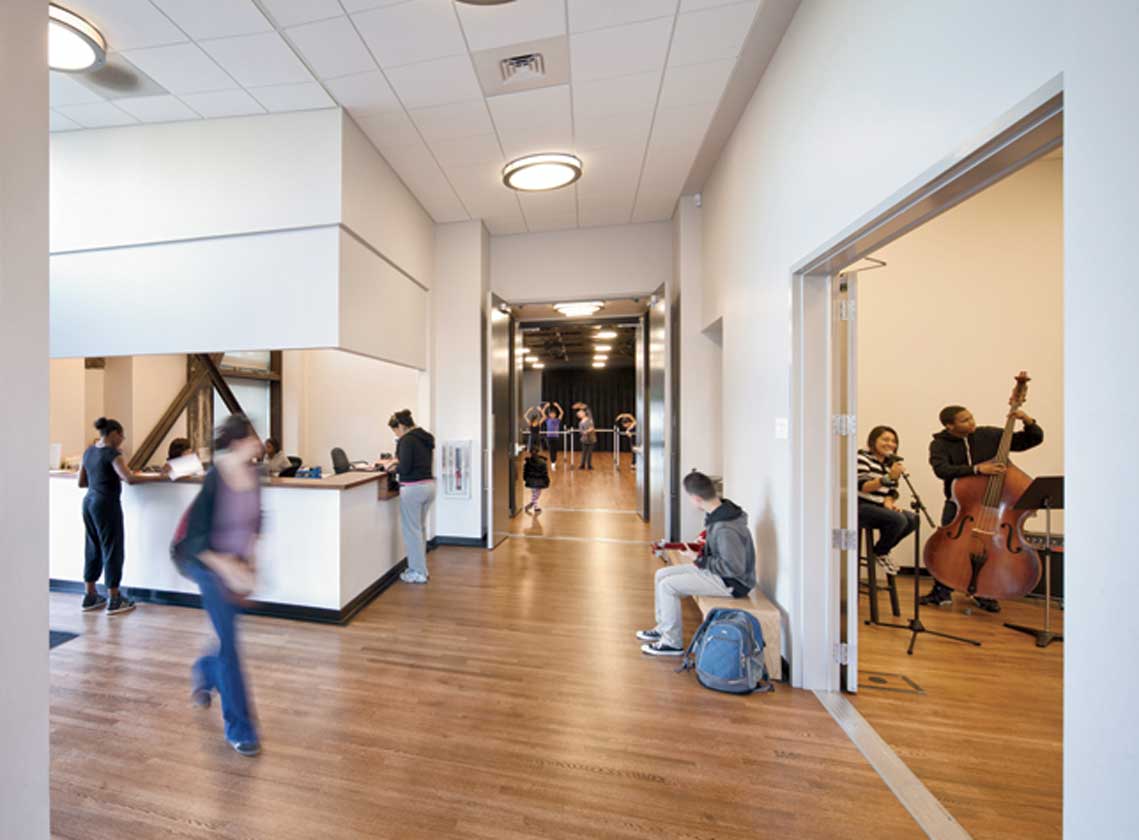 Interior lobby, hallway and reception desk with views into rehearsal spaces