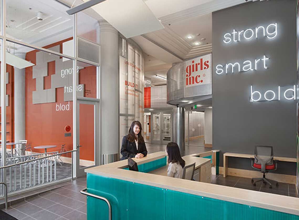 Interior of lobby with reception desk and neon lettering on the wall with words "strong, smart, bold"