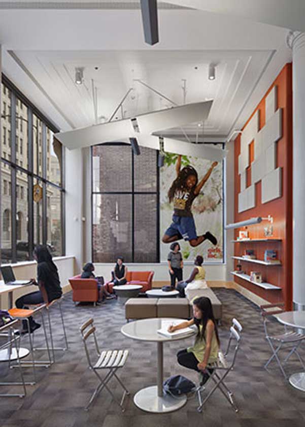 Interior view of lounge with tables and chairs. A large mural of a girl jumping is printed on the far wall