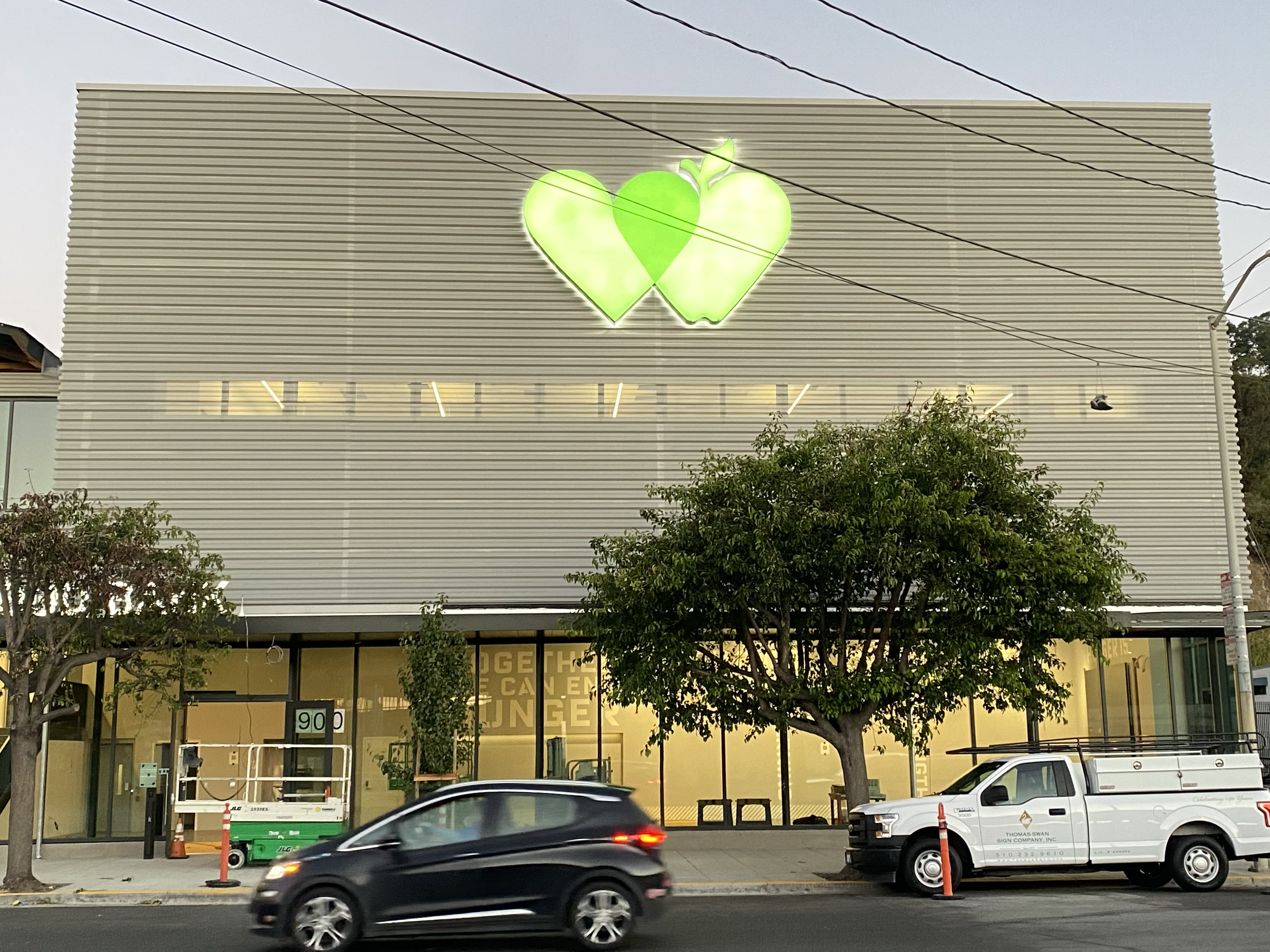 Front facade of building with logo and cars parked in front.