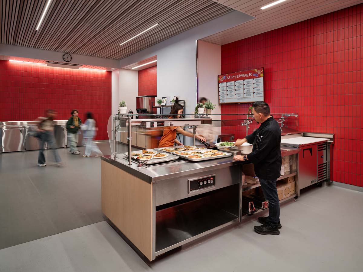 Cafeteria with red walls and gray flooring showing hot food stations.