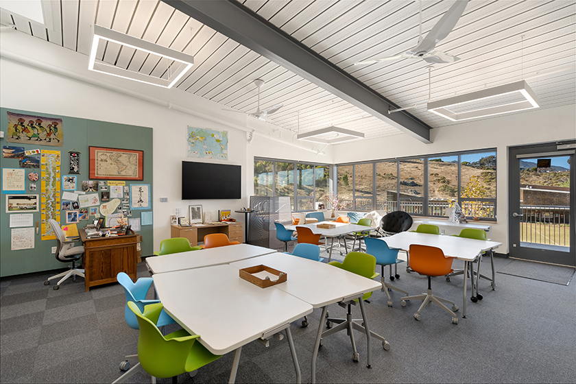 Interior view of bright modern classroom with rearrangeable tables and rolling chairs in bright accent colors