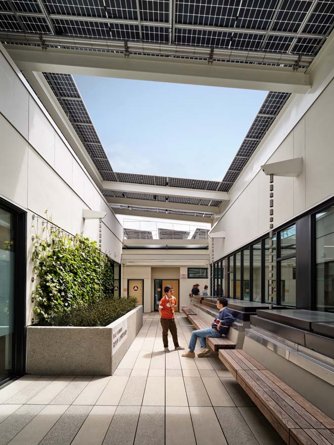 Exterior roof showing benches and students sitting near planters.