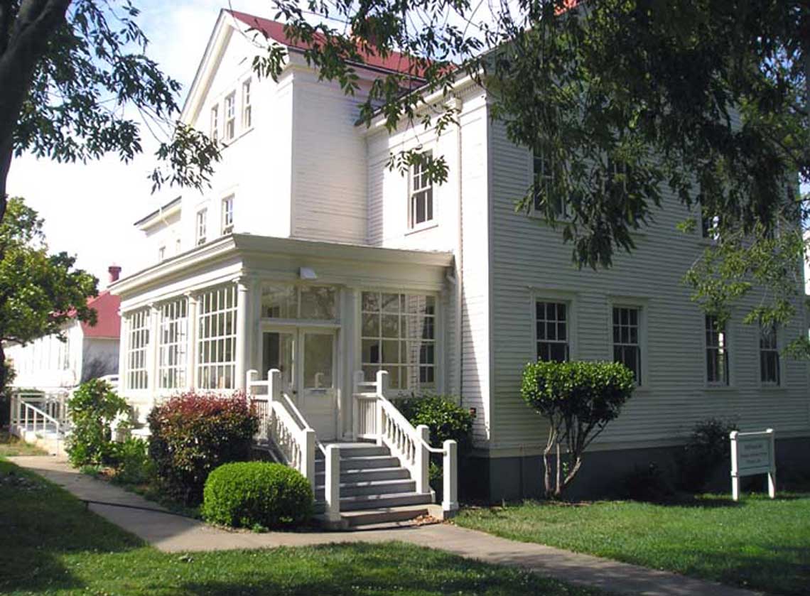 Exterior view of back entrance of a historic building with staircase descending to lush landscape