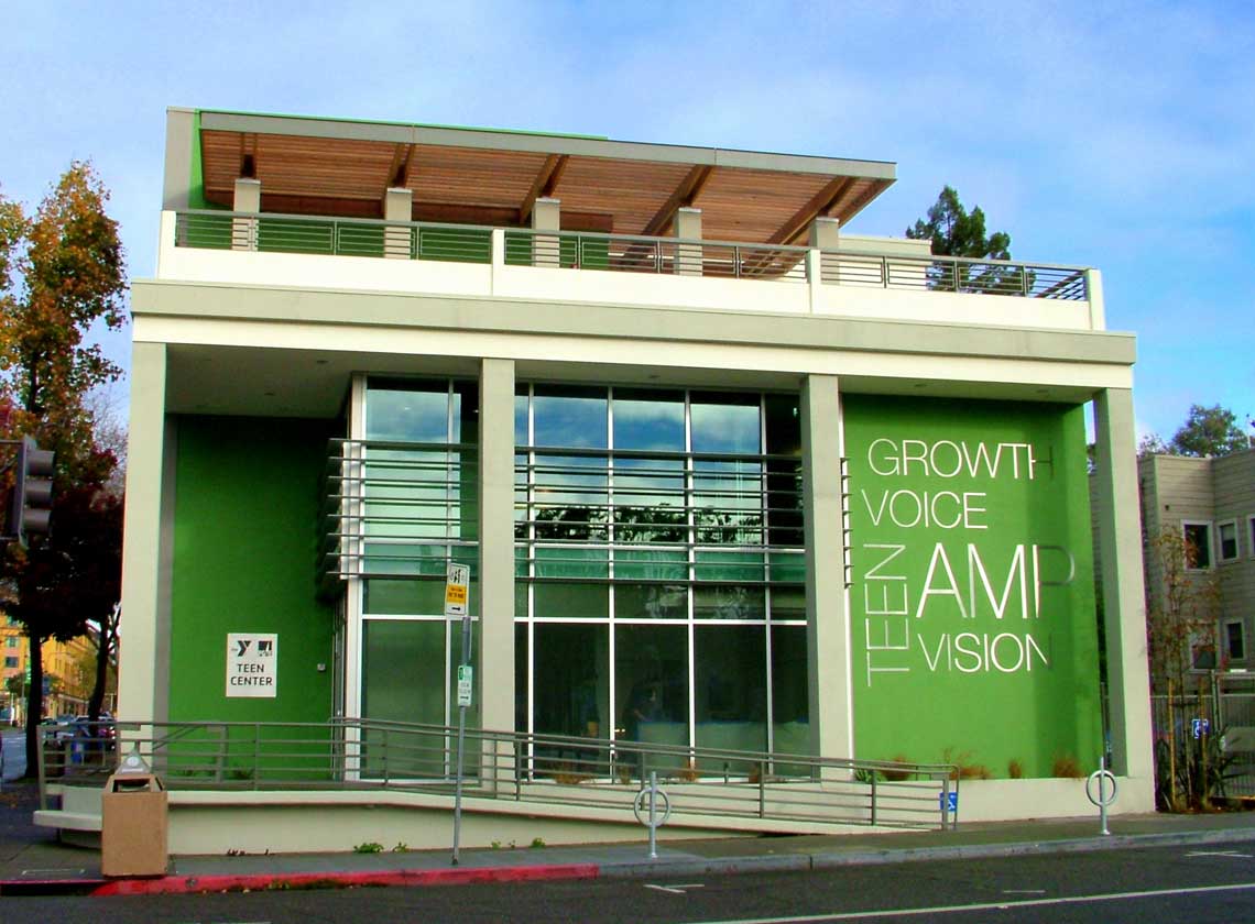 Front view of building entry from street level with bright green façade walls and large graphic words