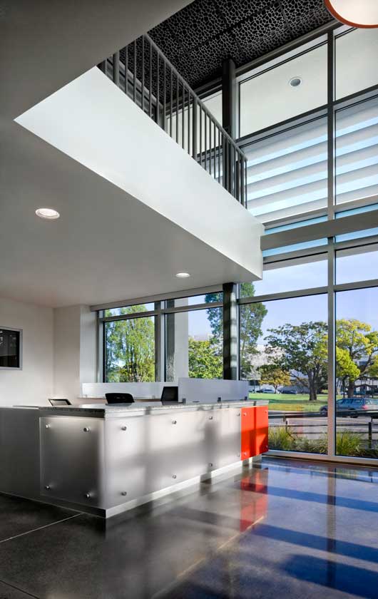 Interior view of lobby reception with view to street through large double-height floor to ceiling windows