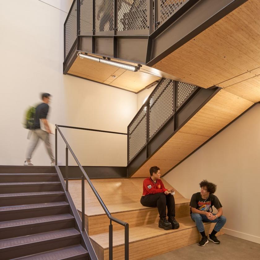 Interior view of open stairway with students gathered on wooden bench seating