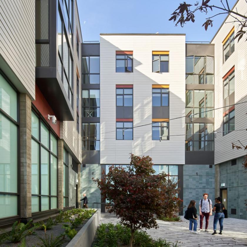 Daytime view of students chatting in a courtyard surrounded by housing units