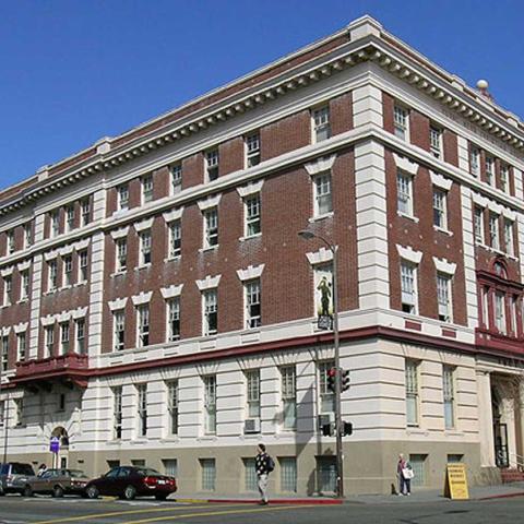 Exterior daytime corner view of ornate, historic, five-level red brick structure