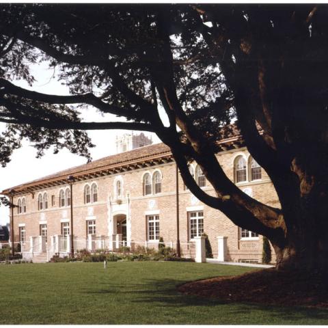 Exterior facade of historic brick building with tree in front.