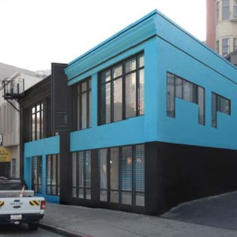 View from street of two story building painted bright blue on the second floor and black on street level.